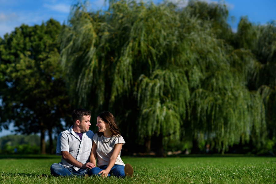 A cute couple sit in the grass and talk about thier future in their penn treaty park engagement session.